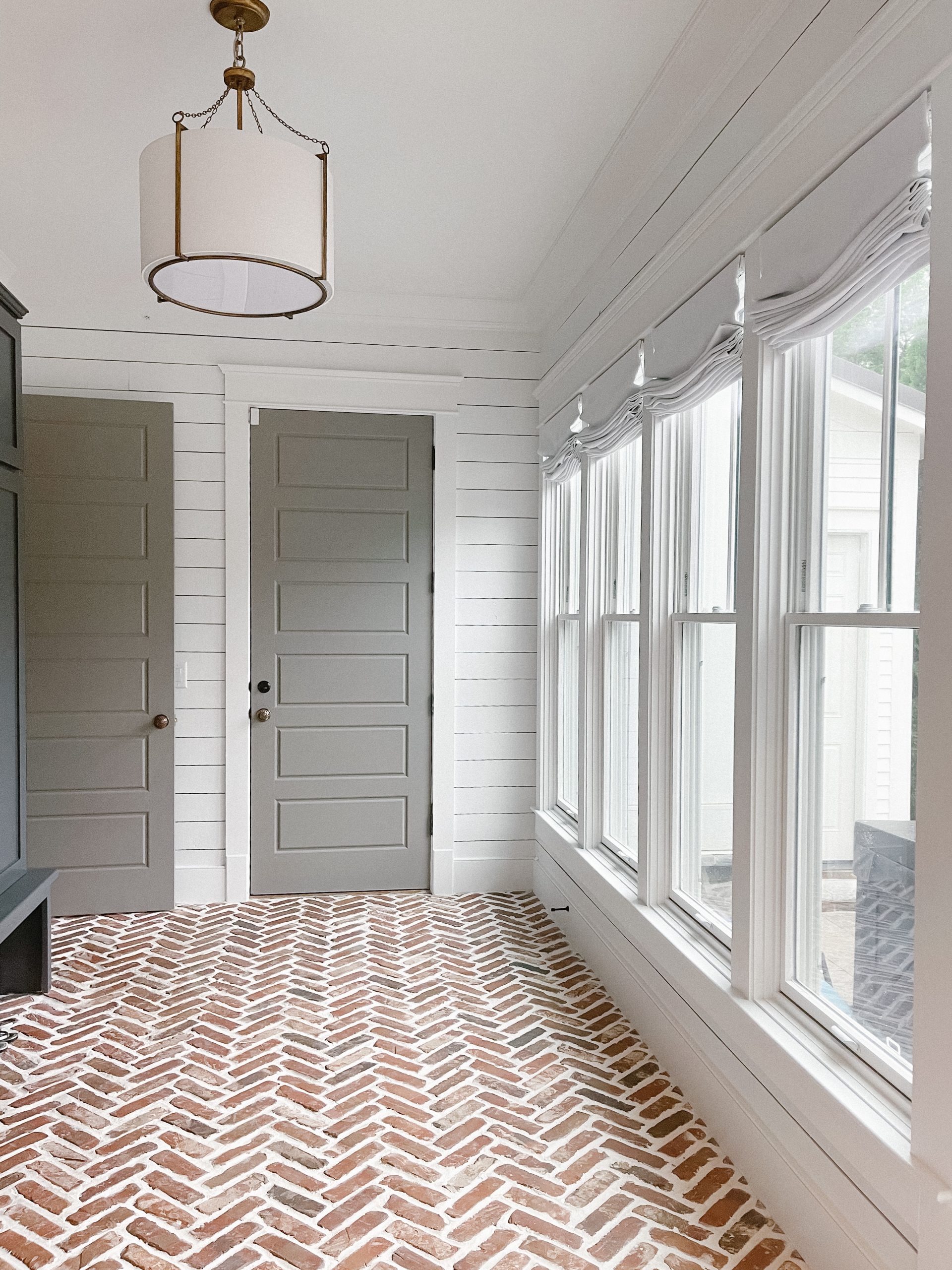 coastal mudroom makeover nashville, tn herringbone brick floors navy built-in cabinets white shiplap